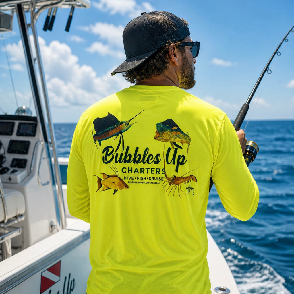 Man on a boat wearing a bright yellow 'Bubbles Up Charters' shirt with fishing gear.